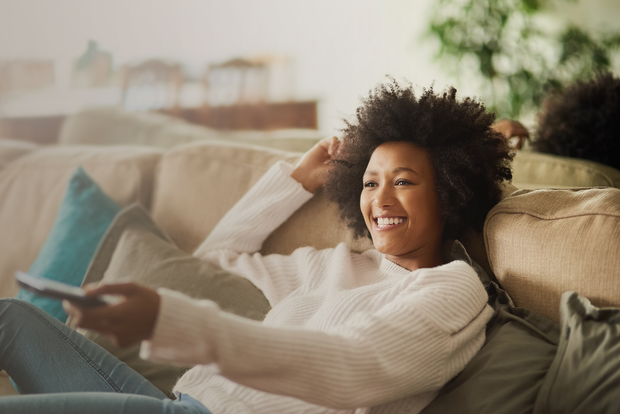 Shot of a young woman relaxing on the sofa at home and watching tv